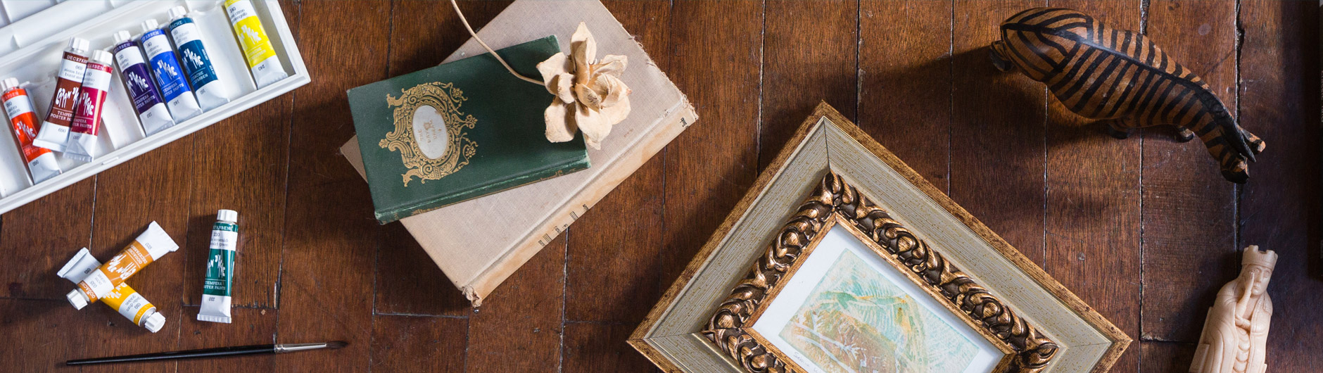 Paints, books, and a framed photo on a dark hardwood floor